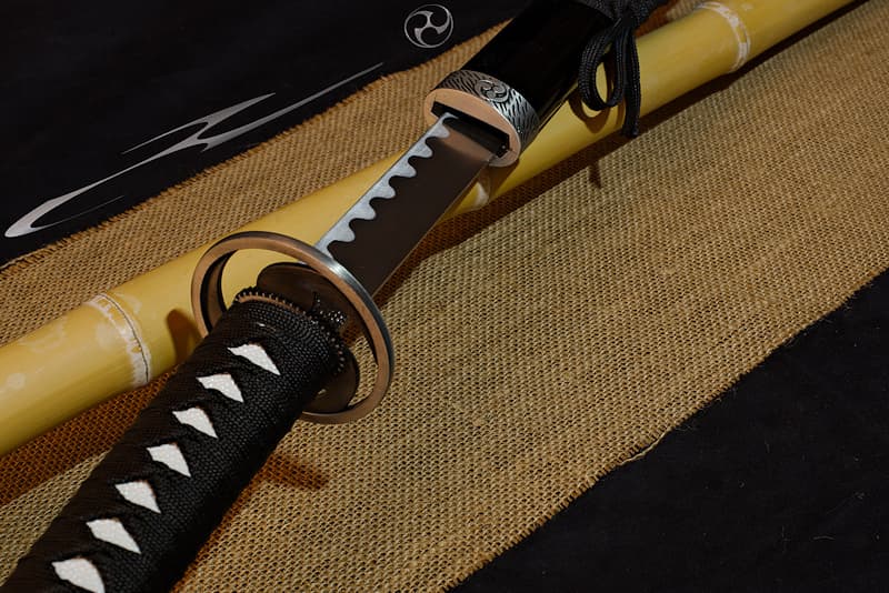 Katana de décoration, saya noire arborant un Mitsu Tomoe, kashira, tsuba et koiguchi Mitsu Tomoe | Signe distinctif depuis la nuit des temps, je continue à identifier les armoiries comme les logos. Les trois « gouttes » (magatama 曲玉) qui me composent donnent le mouvement, vers la droite ou la gauche.