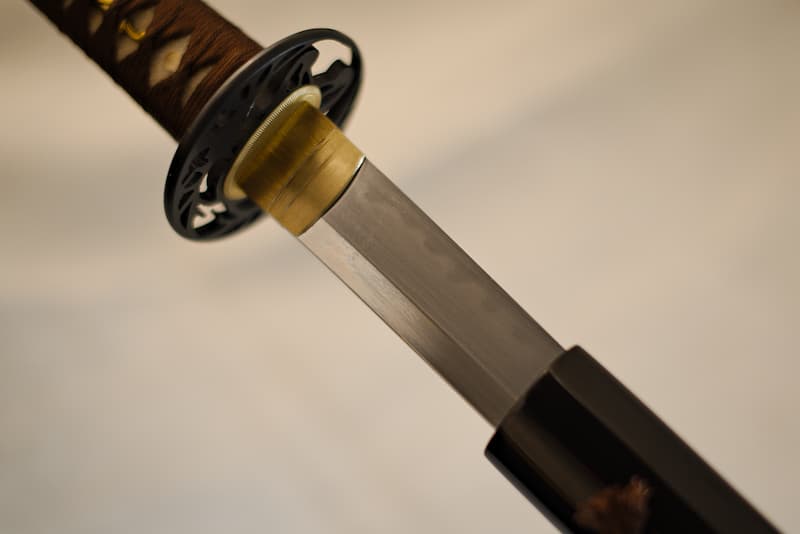 Katana tranchant, acier extra-dur (1095), véritable ligne de trempe (hamon 刃文), avec fourreau (saya 鞘) noir, livré dans un coffret en bois composite contenant un kit d'entretien, un support laqué et une housse de protection en tissu | Portée par mon maître samouraï, j’ai sillonné la terre au point que ma nouvelle monture en porte la trace. Le cordage marron est désormais le symbole de mon nom, Seishi (聖地 Terre sacrée).