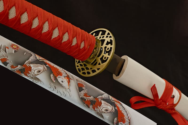 Katana de collection Tsuka-Ito (柄糸) et Sageo (下緒) rouges, Saya (鞘 fourreau) blanche avec sérigraphie représentant des Kujaku (孔雀 paon), variété de carpe Koï (鯉 carpe d’Asie) | Je symbolise la chance, la beauté et la fidélité. C’est la raison pour laquelle mon fourreau (鞘 Saya) est décoré de multiples Kujaku (孔雀), cette variété de carpe Koï (鯉 carpe d’Asie) que la tradition japonaise considère comme un porte-bonheur. Ses reflets métalliques lui donnent d’ailleurs une fière allure.
