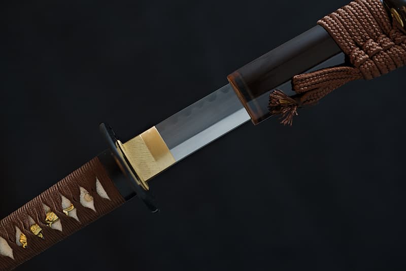 Katana tranchant, acier extra-dur (1095), aiguisé manuellement, véritable ligne de trempe (Hamon 刃文), avec fourreau (Saya 鞘) marron, koiguchi (鯉口), Kurigata (栗形) et Kojiri (鐺) en corne naturelle, livré dans un coffret en bois contenant un kit d'entretien, un support laqué et une housse de protection en tissu