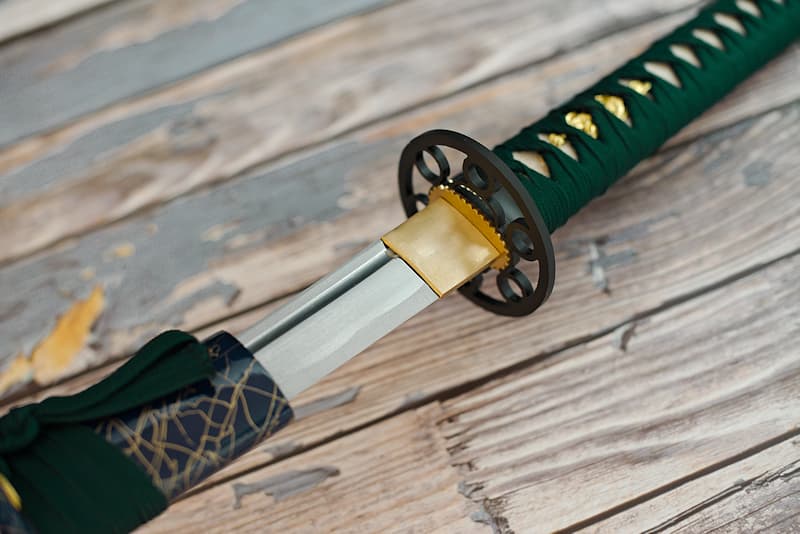 Wakizashi tranchant avec fourreau (saya 鞘) en bois laqué bleu sombre et filaments dorés en relief, tressages (tsuka-Ito 柄糸 et sageo 下緒) vert sombre, livré avec une housse de protection en tissu | Comme pour mon « grand frère », le katana « L’Esprit du Lac », la sylve et l’eau sont mes origines. Le samouraï que j’ai servi avait choisi de vivre aux abords du lac Biwa (琵琶湖), le plus grand lac du Japon.