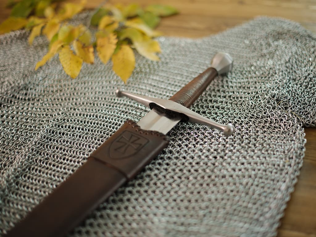Épée médiévale forgée avec fourreau en bois et cuir, sur une cotte de mailles médiévale