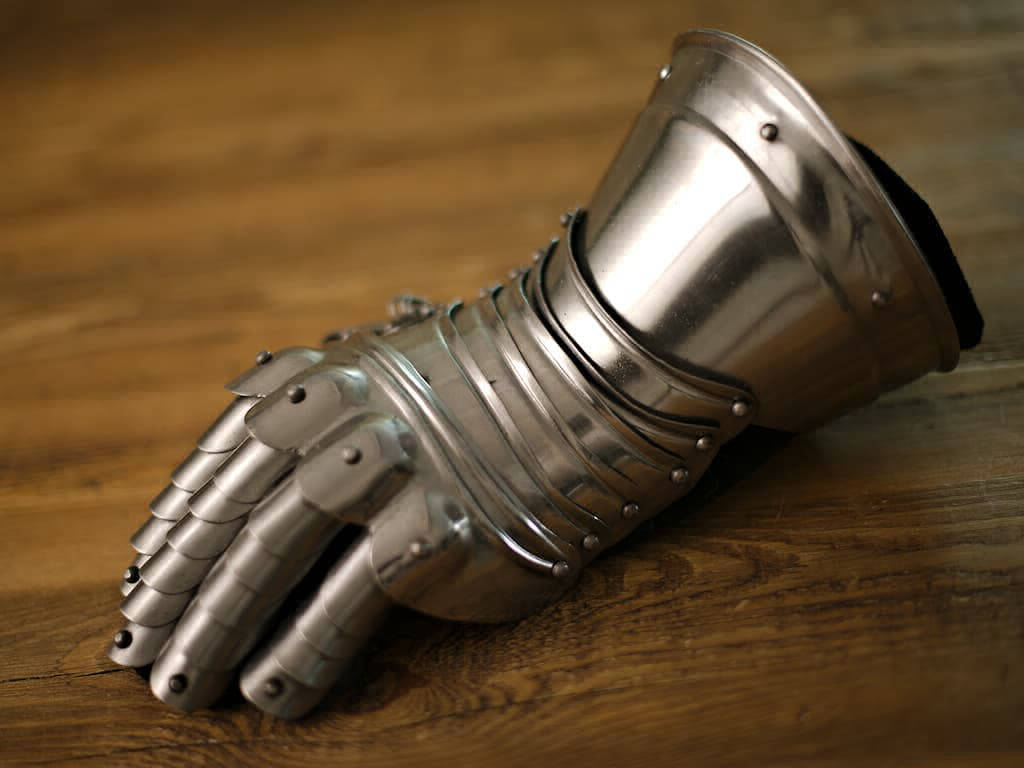 Gantelet articulé posé sur une table médiévale en bois