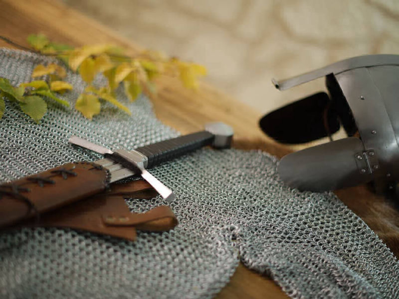 Mise en scène d'une cotte de mailles médiévale avec un casque et une épée de combat Mise en scène d'une cotte de mailles médiévale avec un casque et une épée de combat