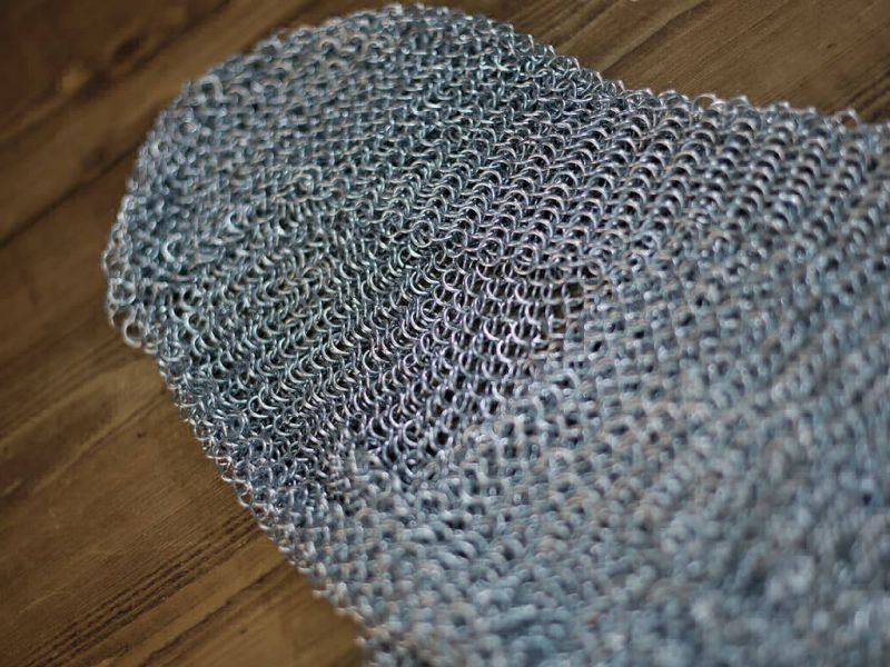 Camail d'armure médiéval posé sur une table médiévale en bois