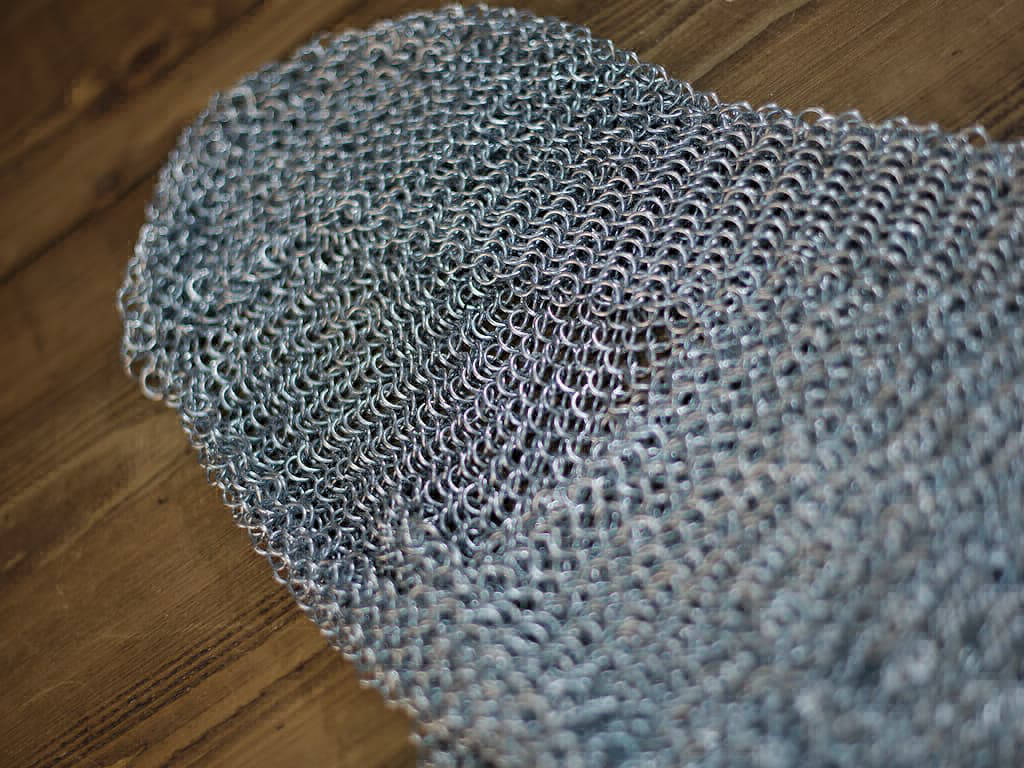 Camail d'armure médiéval posé sur une table médiévale en bois