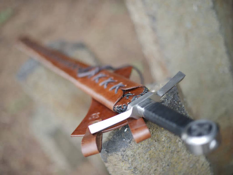 Épée médiévale du chevalier croisé posée sur des pierres verticales naturelles Épée médiévale du chevalier croisé posée sur des pierres verticales naturelles