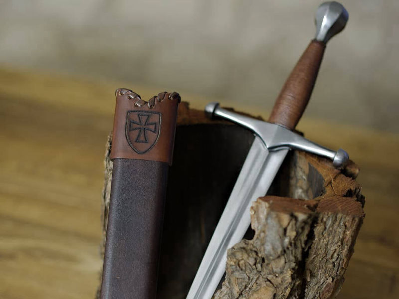 Dague médiévale allemande, posée, avec son fourreau, sur une écorce naturelle