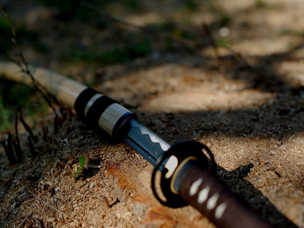 Katana aiguisé bois (mù, 木) métal (jīn, 金), sur le sol couvert de coupeaux de bois Katana aiguisé bois (mù, 木) métal (jīn, 金), sur le sol couvert de coupeaux de bois