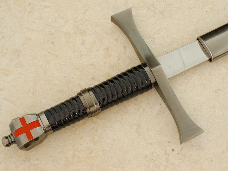 Une main protégée d'un gantelet médiéval prend possession de l'épée templière de décoration Épée templière « Retour de Terre Sainte » #Terressens