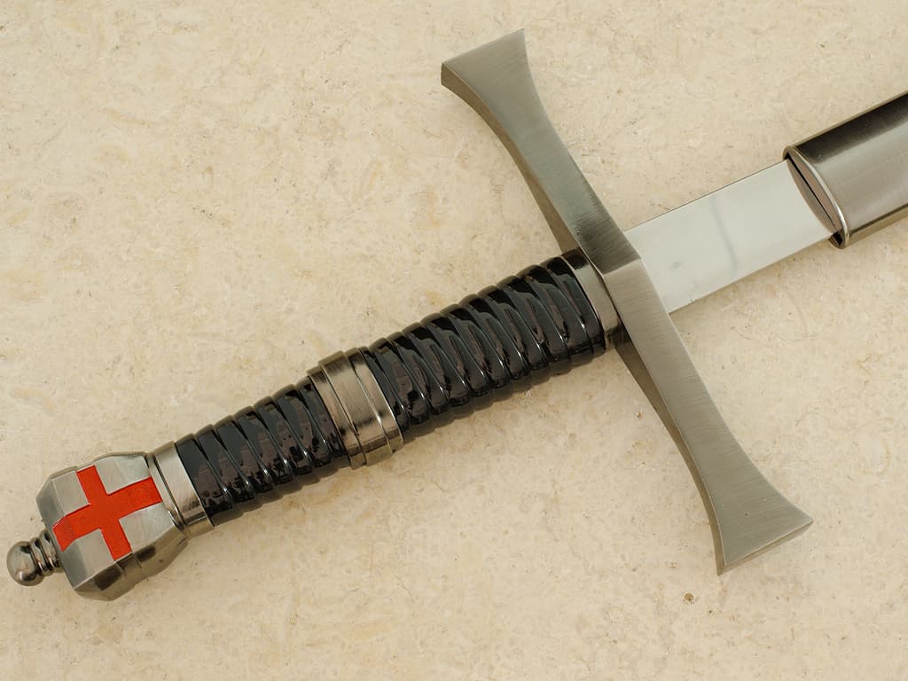 Une main protégée d'un gantelet médiéval prend possession de l'épée templière de décoration Épée templière « Retour de Terre Sainte » #Terressens